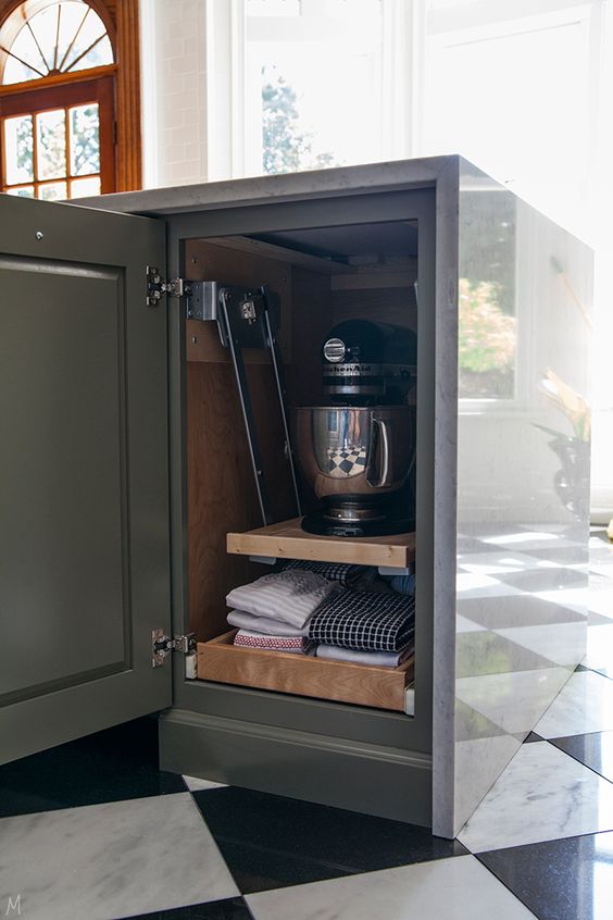 A small and narrow kitchen cabinet with retractable and lifting up shelves that hold kitchen appliances and kitchen towels.