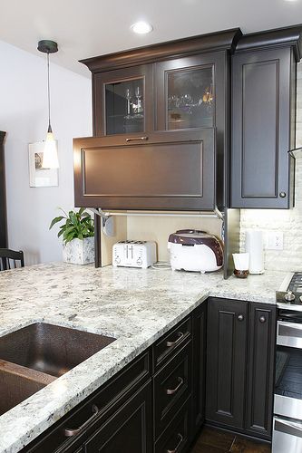 A space under a cabinet can get a comfortable raising door to hide the appliances and get a stylish look.