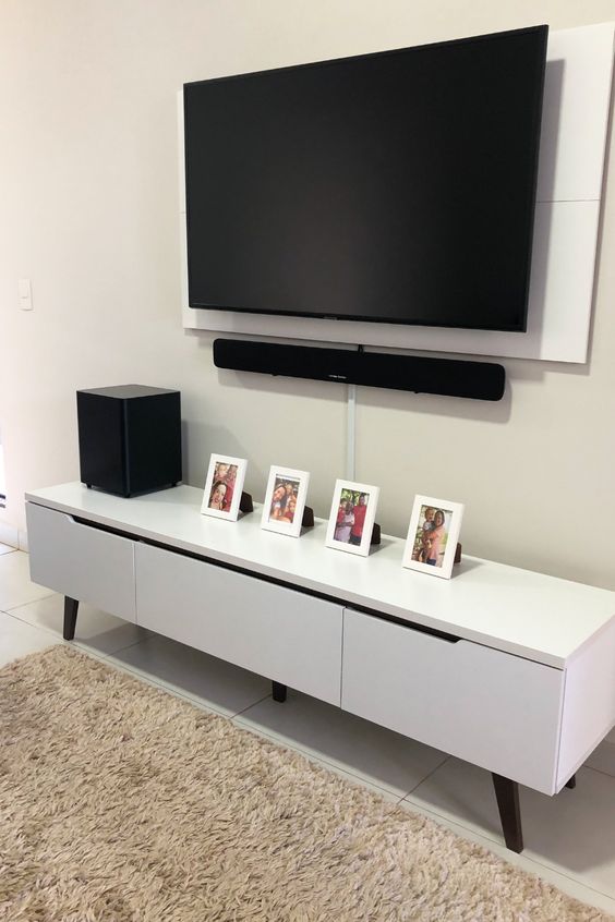 A neutral space with a sleek and stylish media console, a wall-mounted TV with all the cords hidden away in a tube attached to the wall.