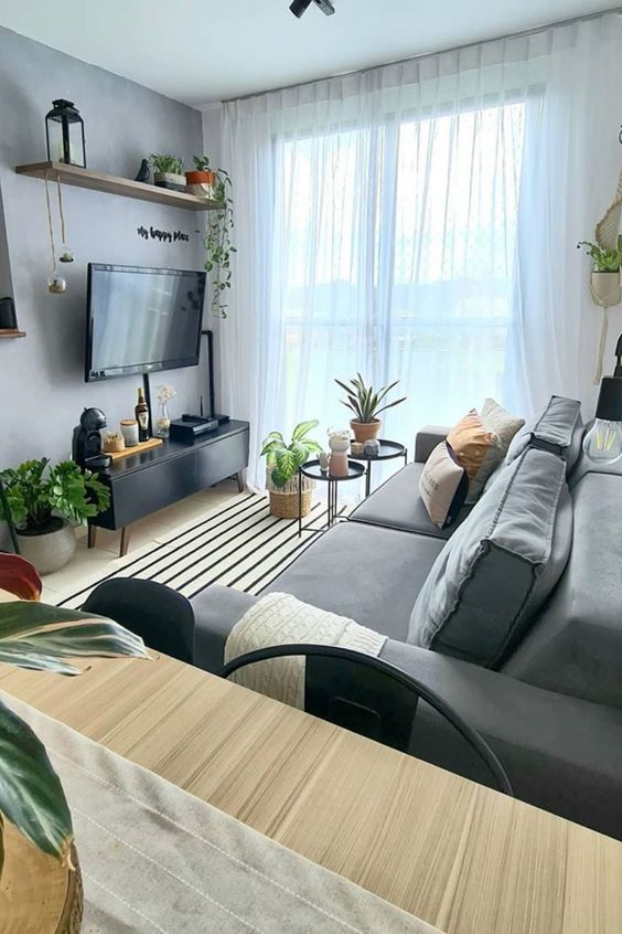 A stylish small Scandi living room with a wall-mounted TV and all the wires hidden inside black wire tubes attached to the wall.