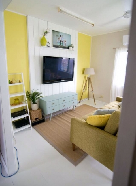 A bright living room with a white shipalp accent on the wall used to make the TV stand out and at the same time hide the wires away.