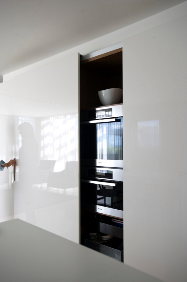 An oversized glossy sleek cabinet with a sliding door that hides all the kitchen stuff you may need and keeps the space neat.