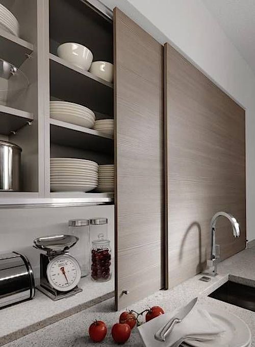 Sleek sliding doors hiding open storage cabinets with not only appliances but also much other stuff is a genius idea.