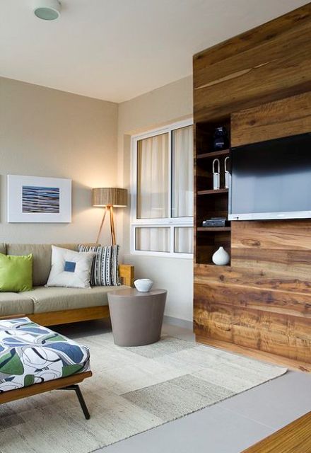 A stylish mid-century modern living room done in neutrals and brights, with a stained wooden storage unit and a TV on it, with wires hidden inside the piece.