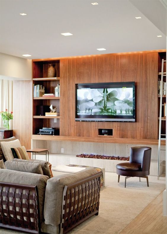 An elegant mid-century modern living room with a large stained wood storage unit with a wall-mounted TV and all the wires hidden inside.
