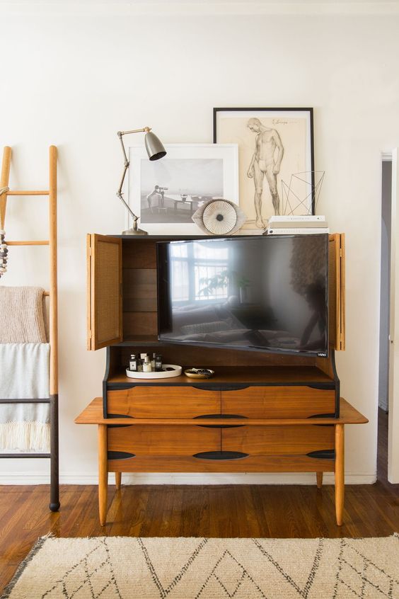 A vintage rich-stained storage cabinet that holds a TV and can hide it anytime with cane bi-fold doors is a lovely idea for a modern room.
