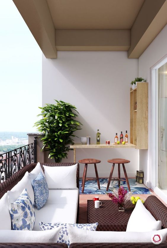 A bold balcony with dark wicker furniture, a small Murphy bar and stools plus a statement plant in the corner.