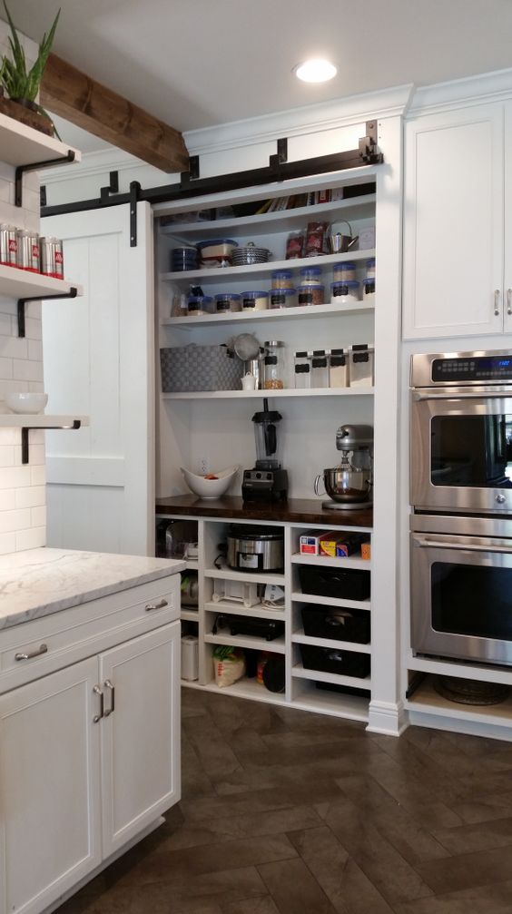 A built-in pantry with a sliding door holds various appliances, spices, food, jars and tableware is a very smart solution to hide everything.