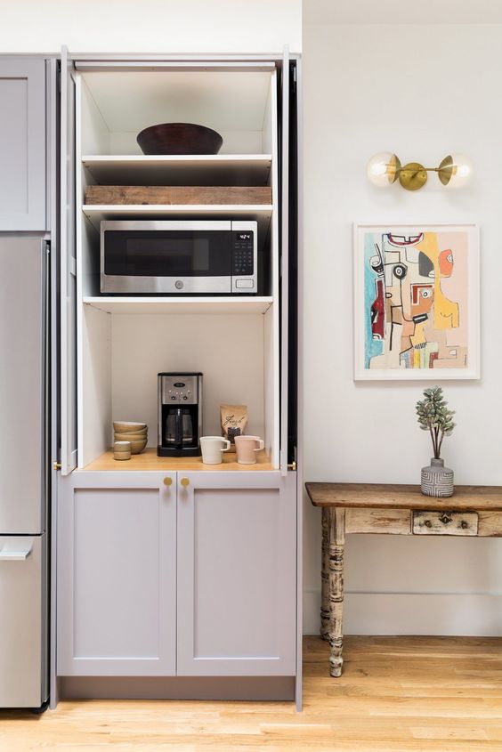 A cabinet with shelves that hides several appliances and creates a mini tea and coffee station you may use.