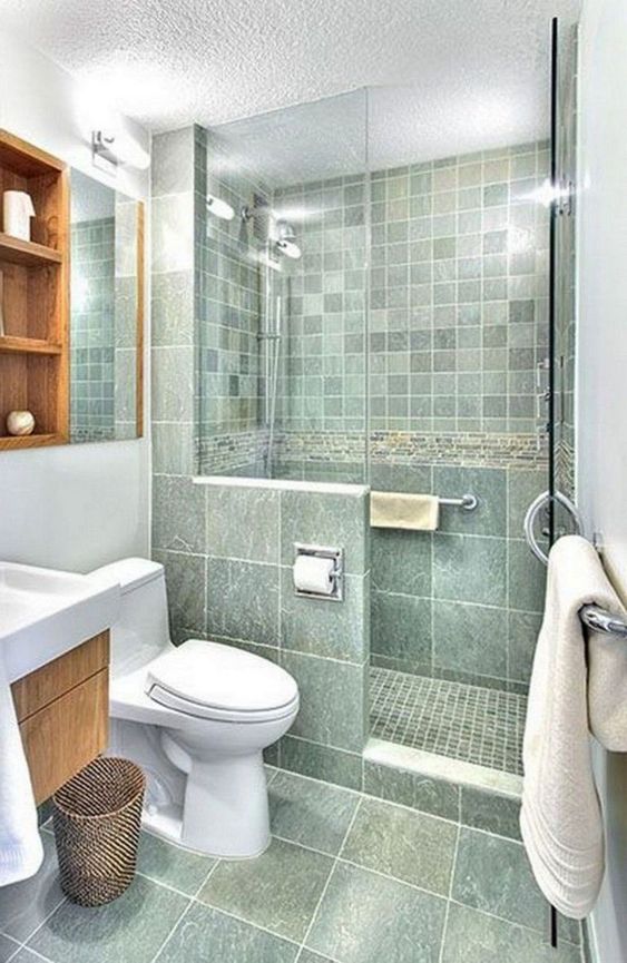 A catchy green bathroom with a small shower space, a stained vanity and a shelving unit, white appliances and white textiles.