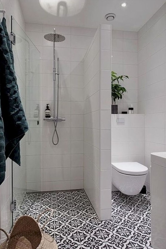 A contemporary bathroom features mosaic tiles and white wall tiles. Potted greenery and a storage basket add a refreshing touch.