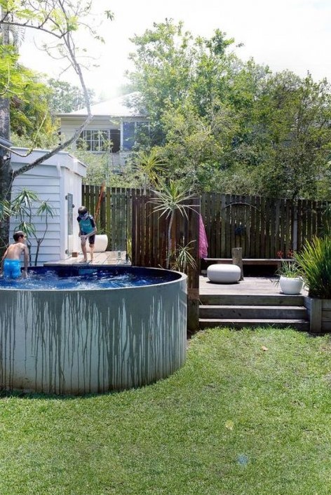 A contemporary deck with some wooden furniture and a raised round tank pool next to it are perfect for kids.