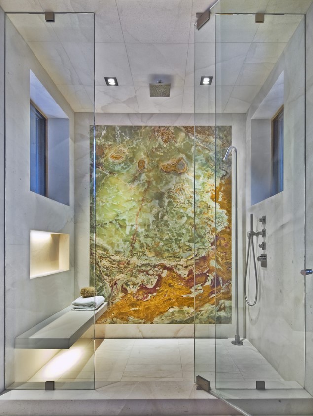 A fantastic neutral shower clad with white marble tiles and a gorgeous stone wall for an accent, a bench and illuminated niches.