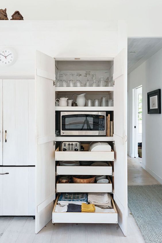 A functional cabinet with shelves and mini drawers holding glasses, mugs, cups and some appliances is a very smart idea.