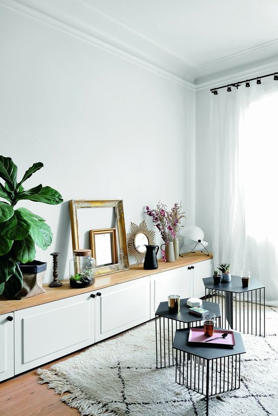 A long white storage unit of IKEA Metod with shaker doors, a wooden tabletop, greenery, grames and decor.