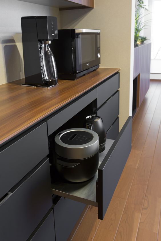 A minimalist black kitchen with an oversized drawer with black appliances keep the kitchen neater and decluttered.