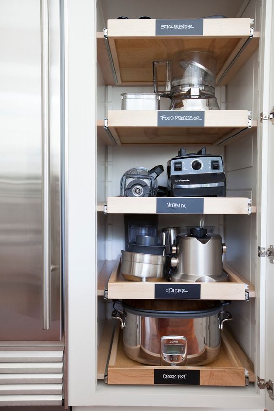 A narrow and tall cabinet with retractable shelves and various kinds of appliances is a cool way to store them without cluttering the space.