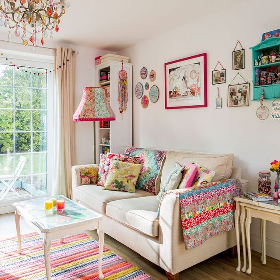 A summer living room with a bold gallery wall, printed pillows and a blanket, a bright lamp and chandelier.