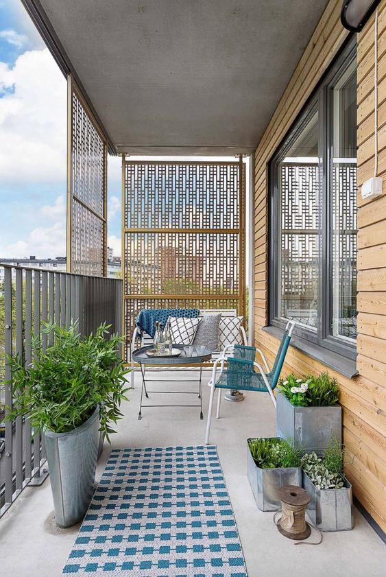 A tiny and cozy space with metal plants with greenery, metal and wicker furniture and blue touches.