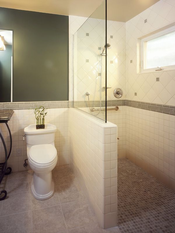 A catchy bathroom with a black wall, neutral tiles cladding the shower space and a half wall with a glass space divider.
