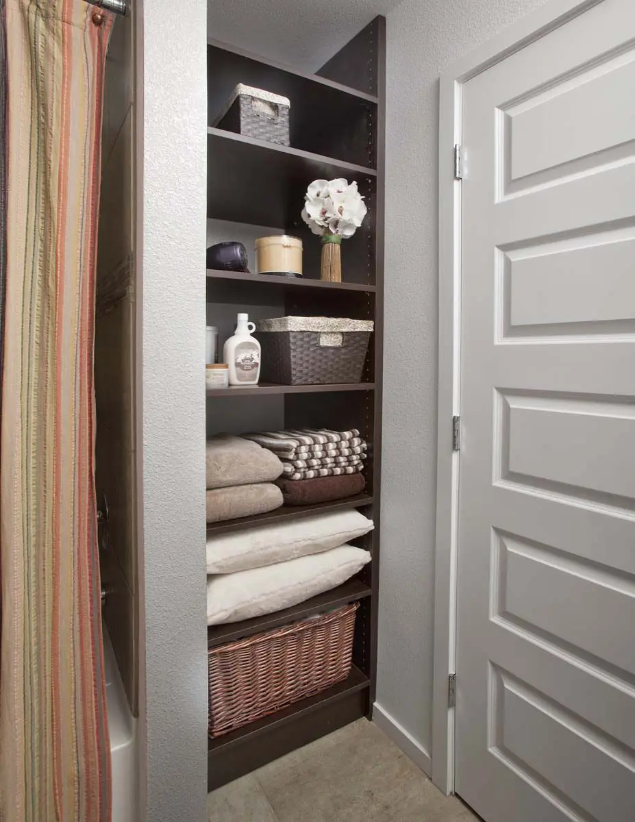 The bathroom is done with dark-stained built-in shelves, where everything necessary can be stored.