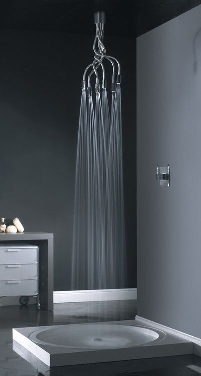 A super creative ultra-modern bathroom with grey walls, a round shower floor and a creative shower head with multiple faucets.