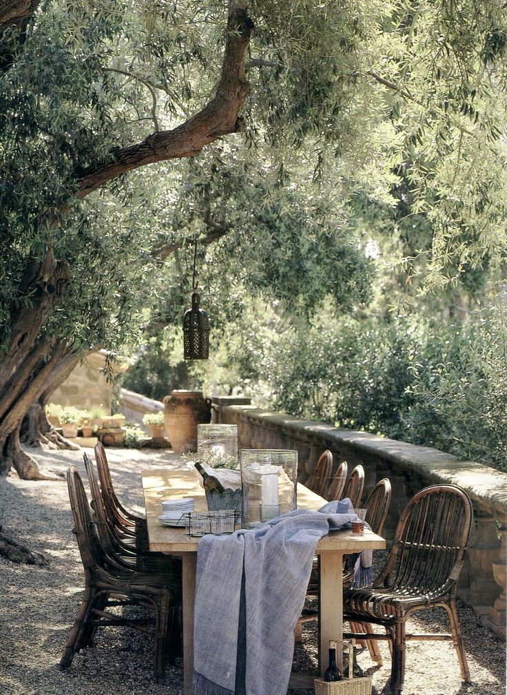 A summer terrace with a dining space in Mediterranean style, with wooden and rattan furniture and neutral textiles.