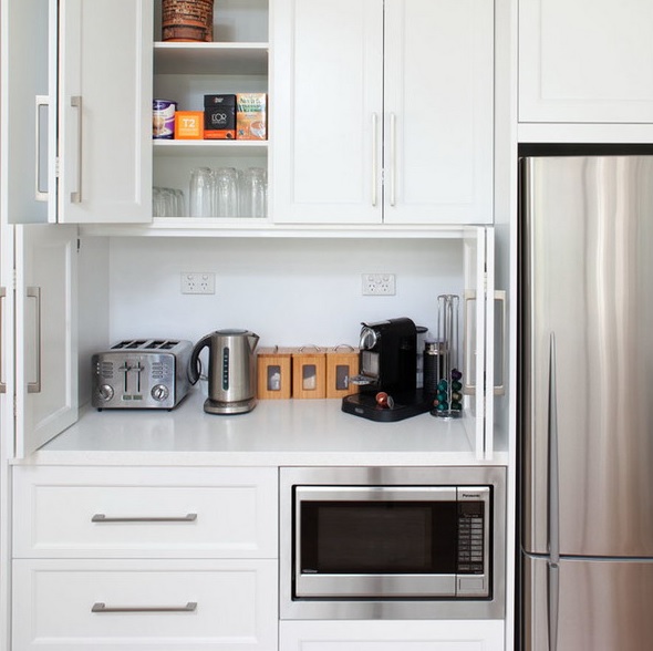 A cabinet with folding doors, a coffee machine, a kettel and a toaster plus mugs and sugar is a perfect breakfast station.
