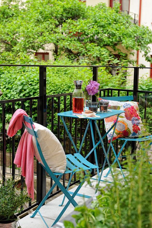 Blue metal furniture, colorful printed textiles, lots of greenery here and there for a bold and bright space.