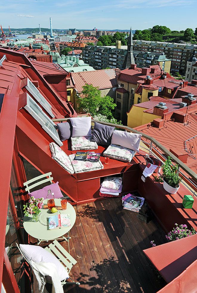 A colorful summer terrace with potted greenery and blooms, printed summer textiles, simple metal folding furniture.