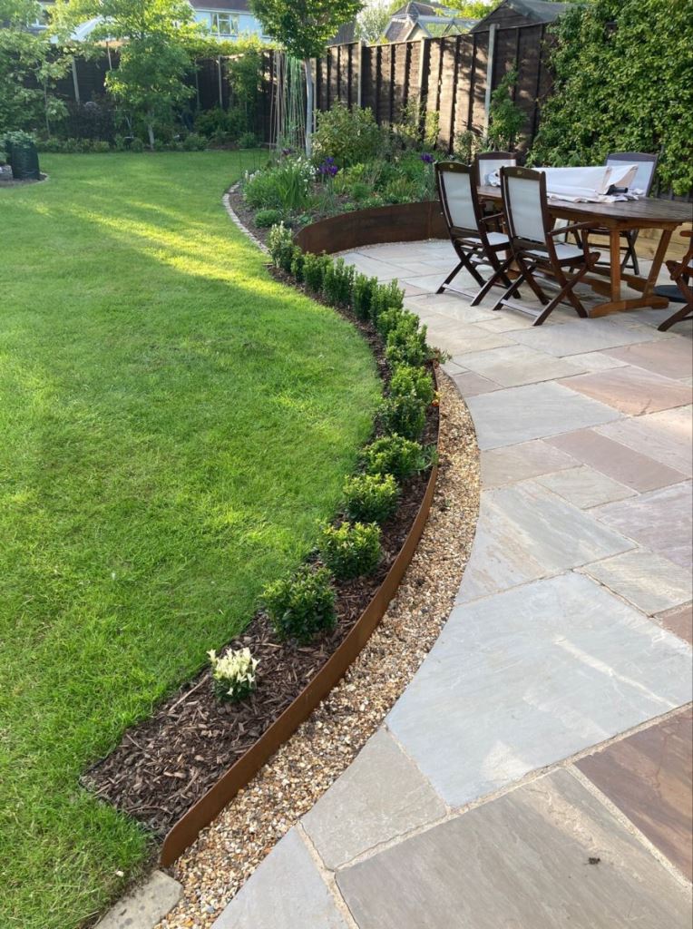 The curved lawn is accented with a long planter with greenery, and these are super trendy touches.