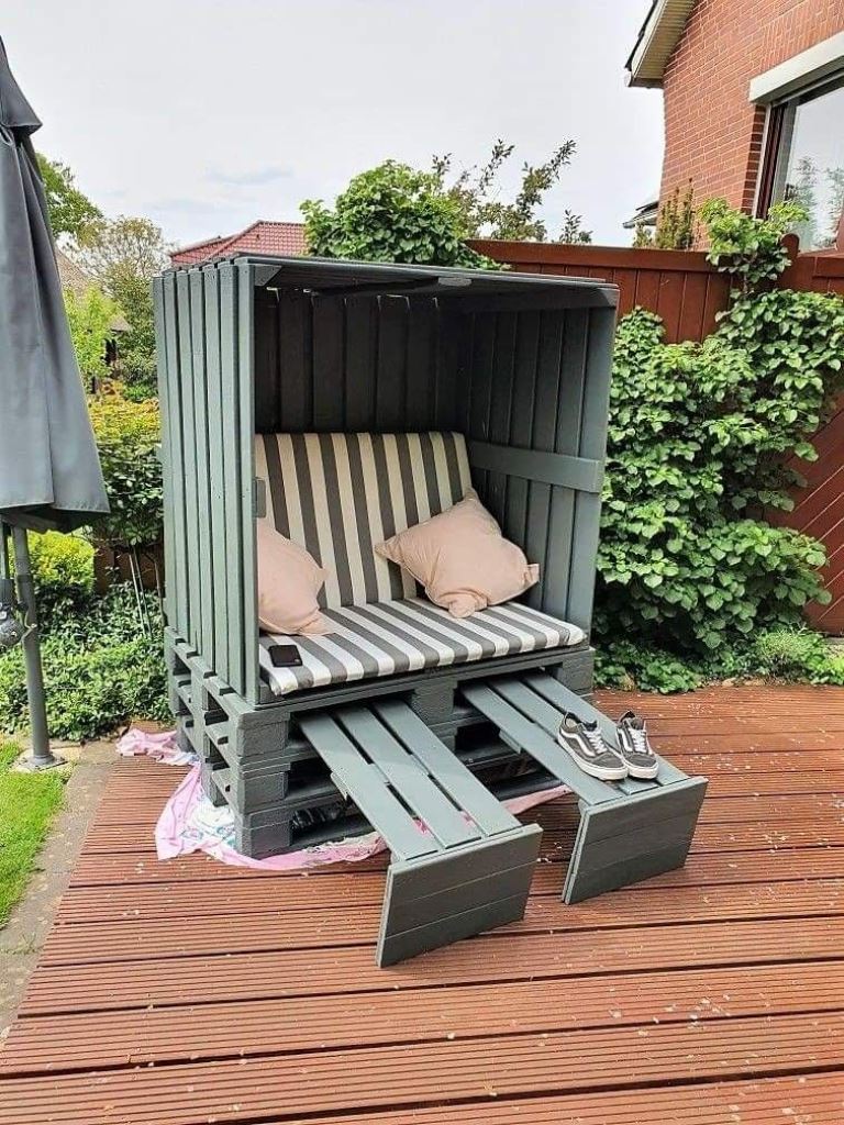 This lovely green arbor features a small sofa with pillows and stands where you can place something.