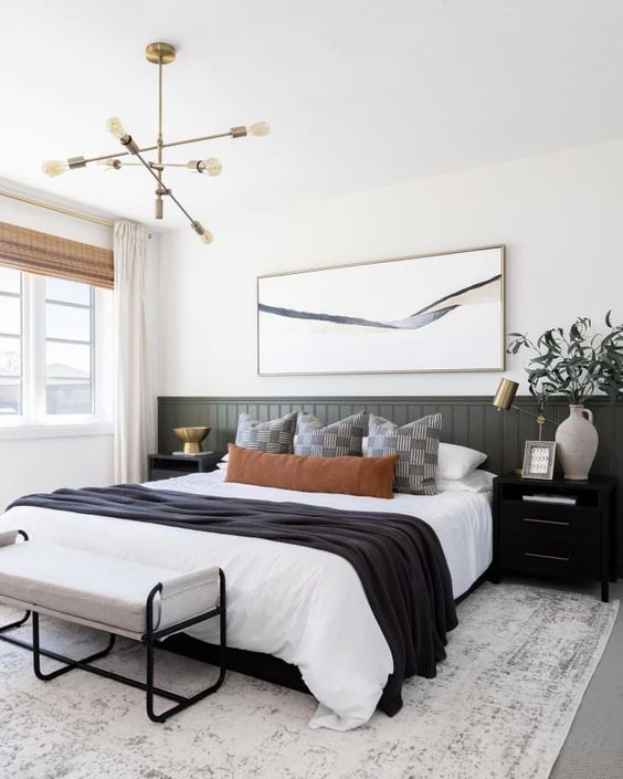 The farmhouse sleeping space accented with an olive green planked headboard, a bed, a bench, matching nightstands and some decor.