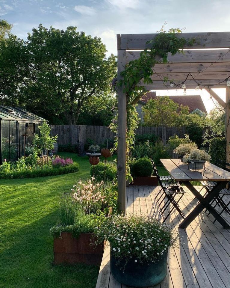 The outdoor dining zone is located on a raised deck and is surrounded with potted blooms and greenery.