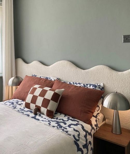 The pretty bedroom is made trendy and whimsical with a creamy boucle wavy headboard added to the bed.