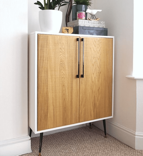 A Metod cabinet placed on legs and renovated with light-colored wooden doors and handles in mid-century modern style.